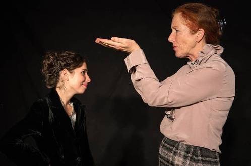 Zwei Personen stehen sich gegenüber und schauZwei Personen, eine gestikuliert mit erhobener Hand, die andere lächelt leicht.en über sich hinweg