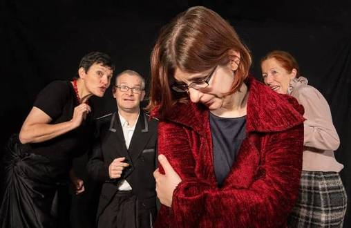 Eine Frau steht im Vordergrund mit dem Kopf nach unten, dahinter stehen andere Menschen und tuscheln.