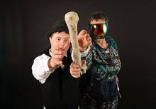 Zwei Personen halten einen großen Knochen, eine trägt ein Visier.